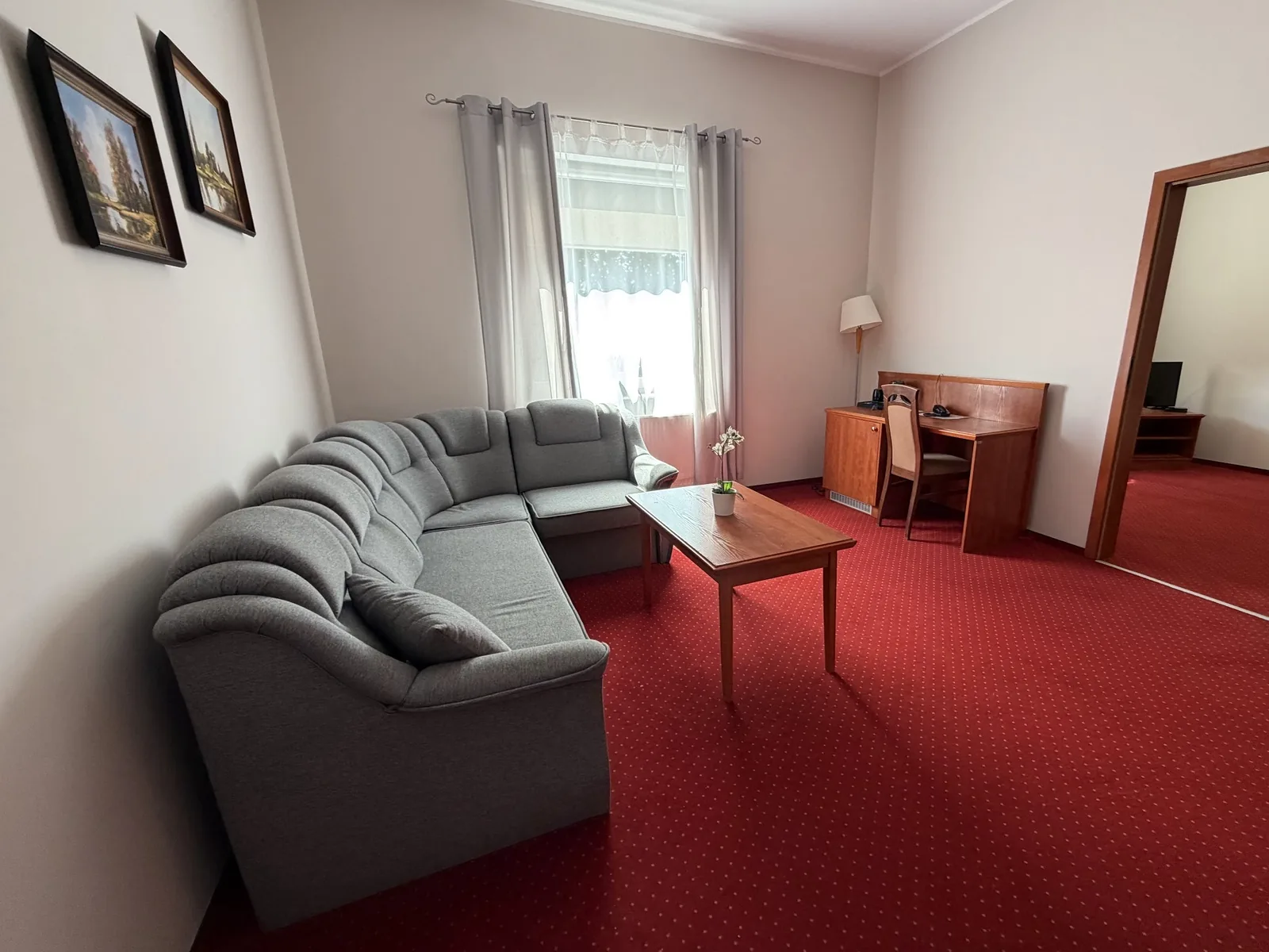 Salon apartamentu z narożnikiem, stolikiem i biurkiem w hotelu Dowhań